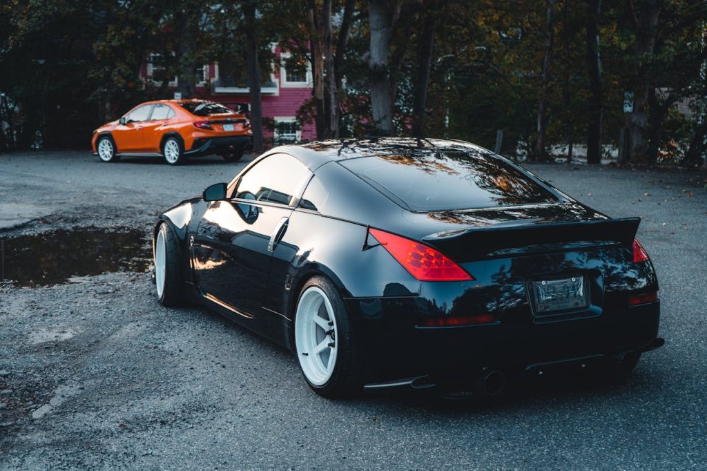 A stylish black Nissan 350Z parked in a woodland area during twilight, showcasing its sleek design.