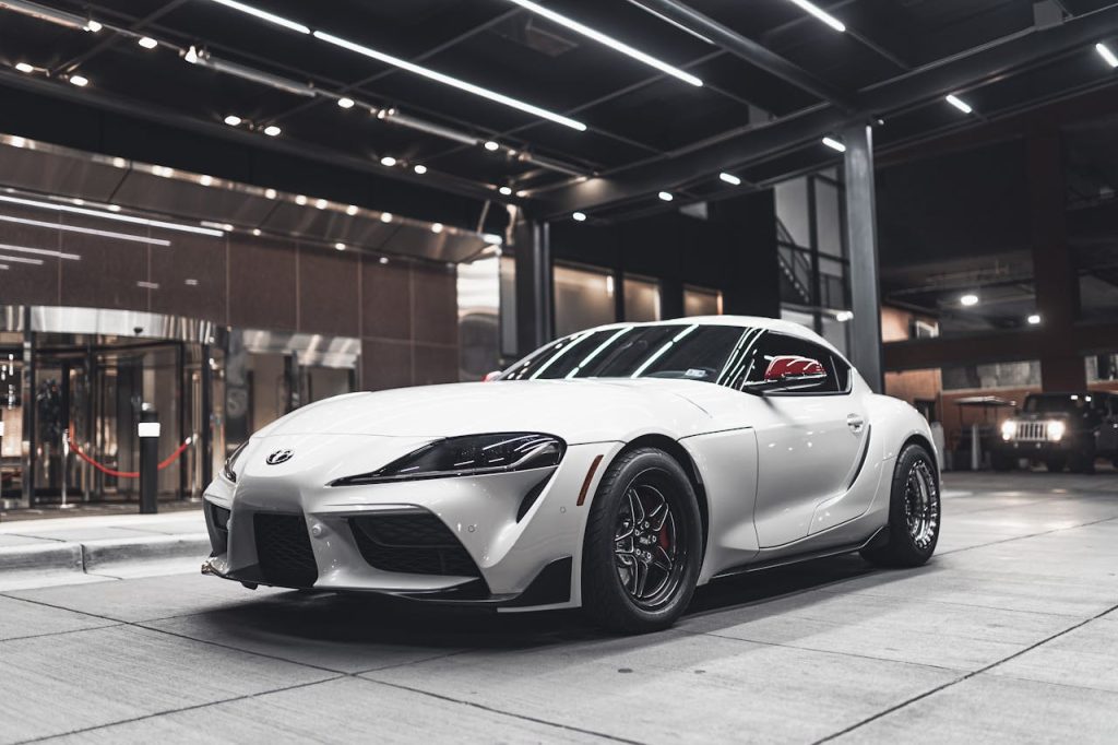 A white sports car displayed indoors, showcasing its design and luxury appeal.